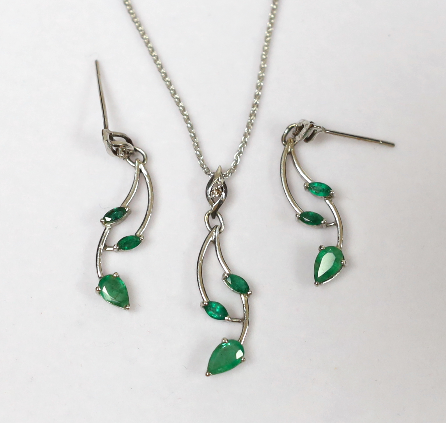 A modern white metal, three stone emerald and single stone diamond set pendant 31mm, on an 18ct fine link chain, 39cm and a pair of matching earrings, gross weight 8.3 grams.
